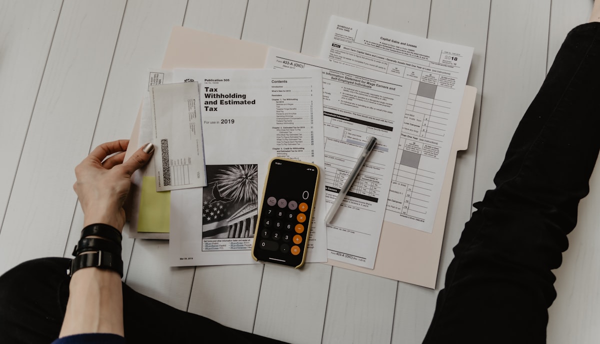 Invoices and a calculator spread across the desk, the numbers being worked